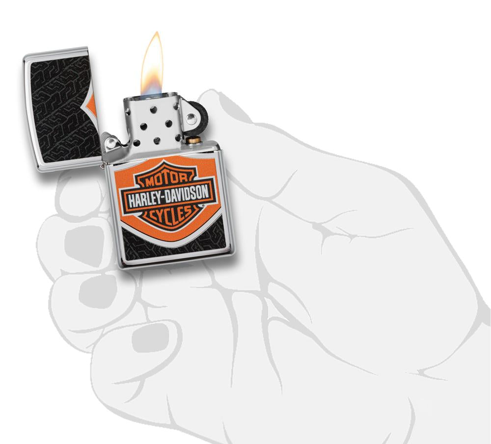 Briquet Zippo chromé avec logo Harley Davidson orange noir blanc, ouvert avec flamme dans une main stylisée